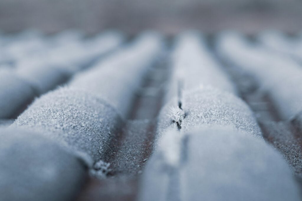 Icy buildup on roof shingles showing early signs of winter weather stress.
